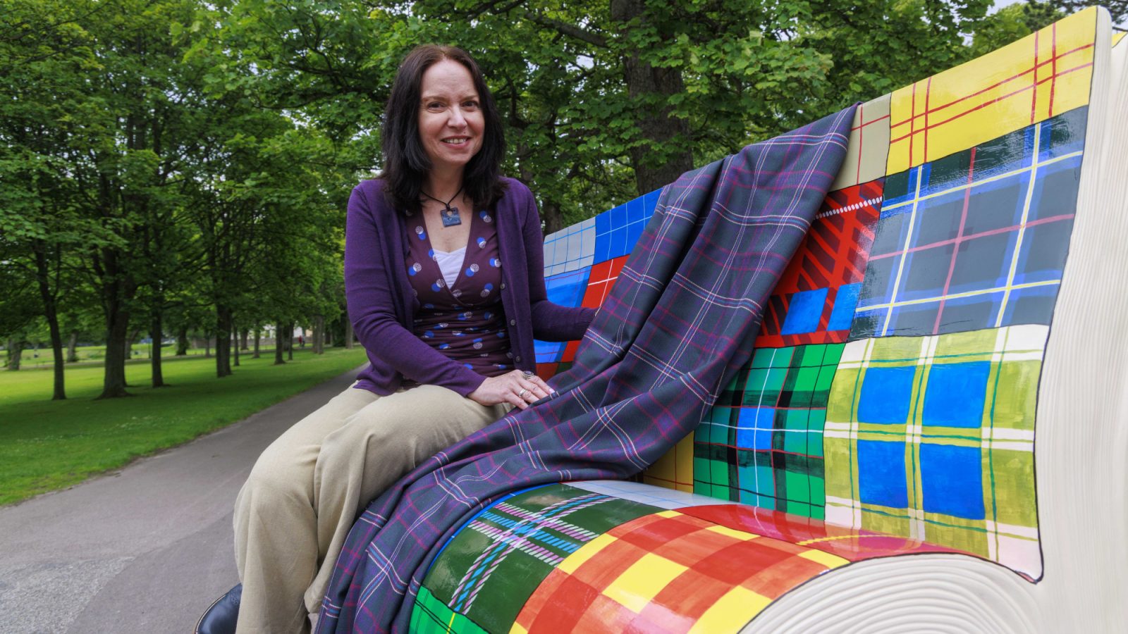 Sandra Russell with All One Clan sculpture and Clan tartan